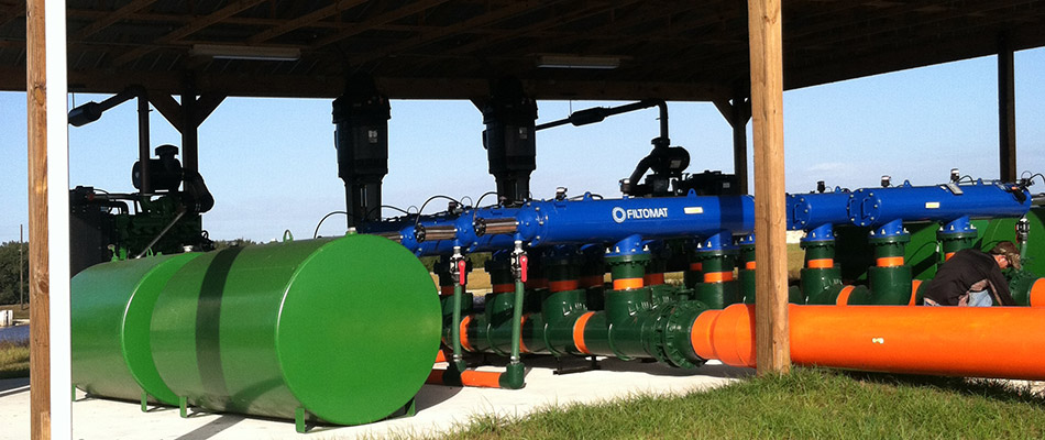 Green, blue, and orange pipes and tanks making up an irrigation system for an aquaculture farm in Texas.